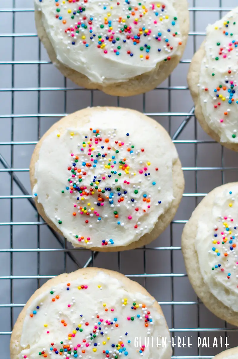 Gluten-Free Sugar Cookies with white frosting and colored sprinkles on a cooling rack