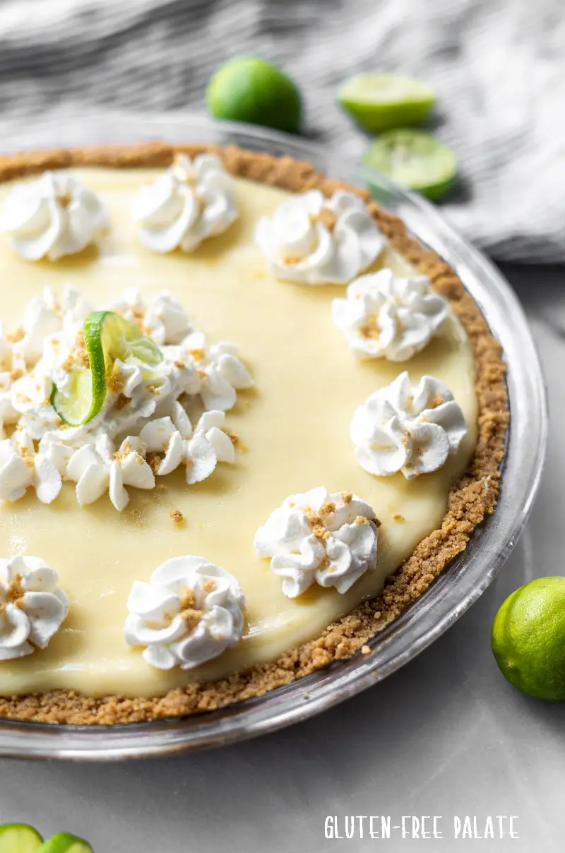 a gluten free key lime pie in a glass pie dish with whipped cream