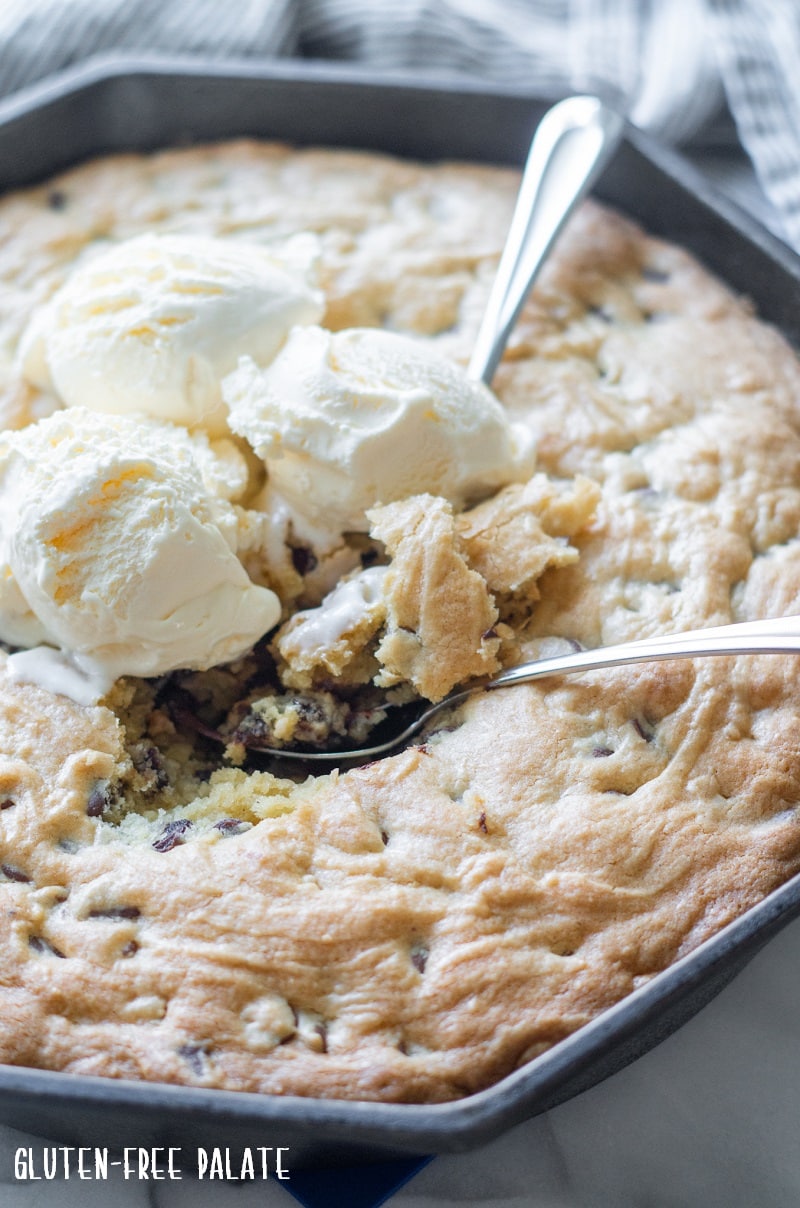 side view of close up of a gluten free chocolate skillet with three scoops of vanilla ice cream on top with two spoons