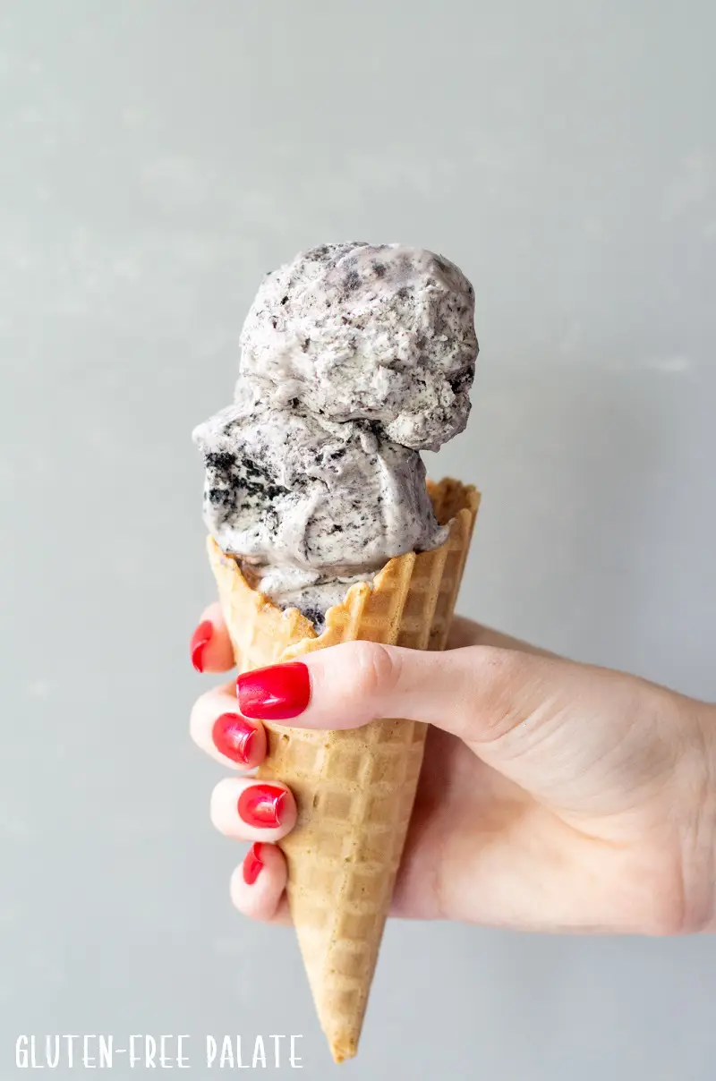 a hand holding a waffle cone filled with gluten free ice cream
