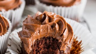 a paleo chocolate cupcake with chocolate frosting, with a bite taken out