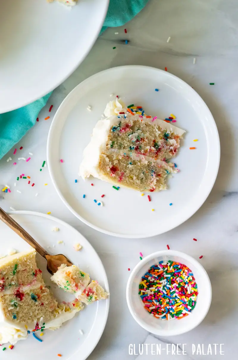 slices of funfetti cake on a white plate next to a bowl of sprinkles