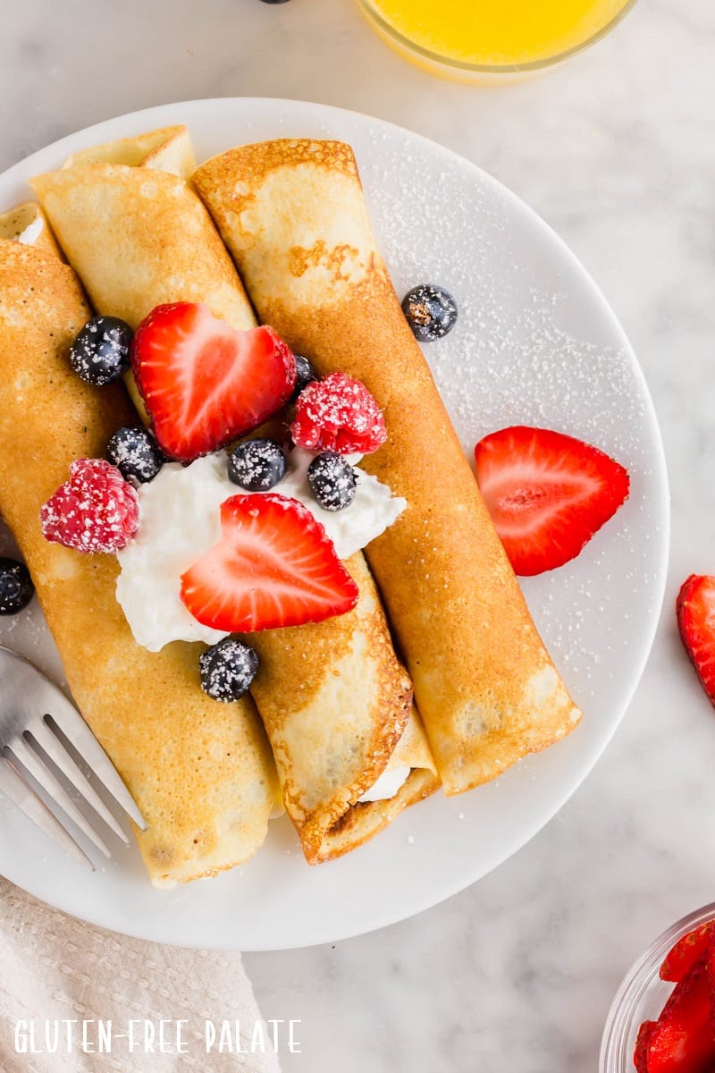 gluten free crepes with whipped cream and strawberries on a white plate