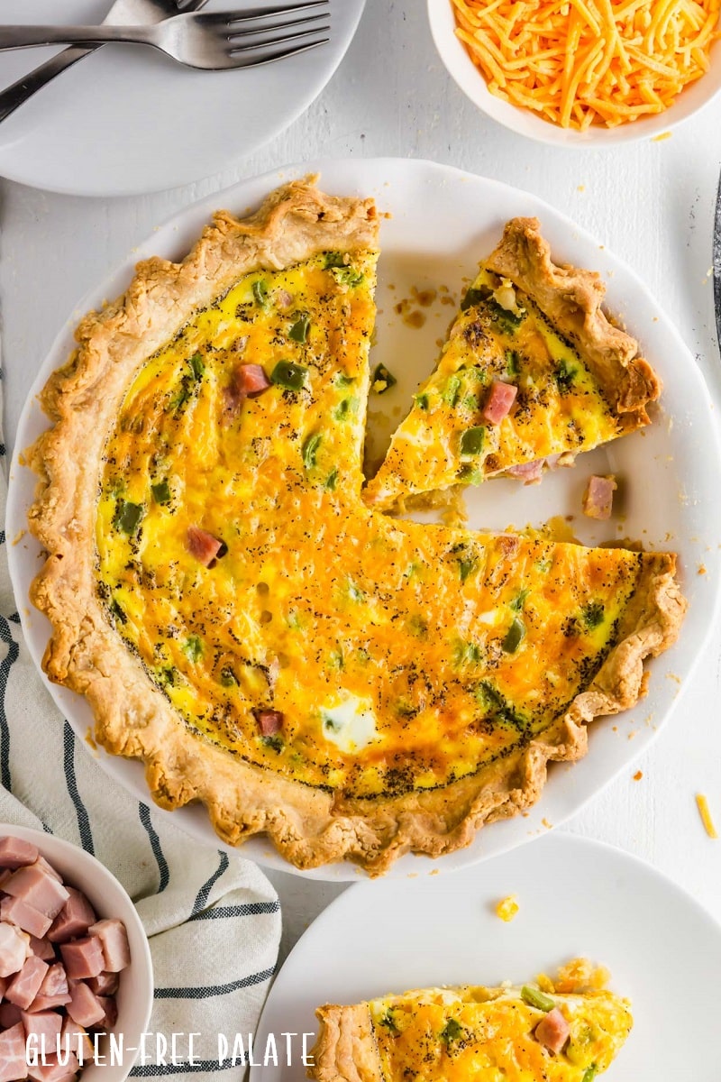 gluten free quiche in a white pie pan with a slice out