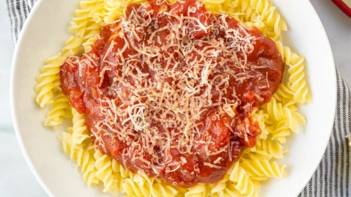 spaghetti sauce over noodles in a white bowl
