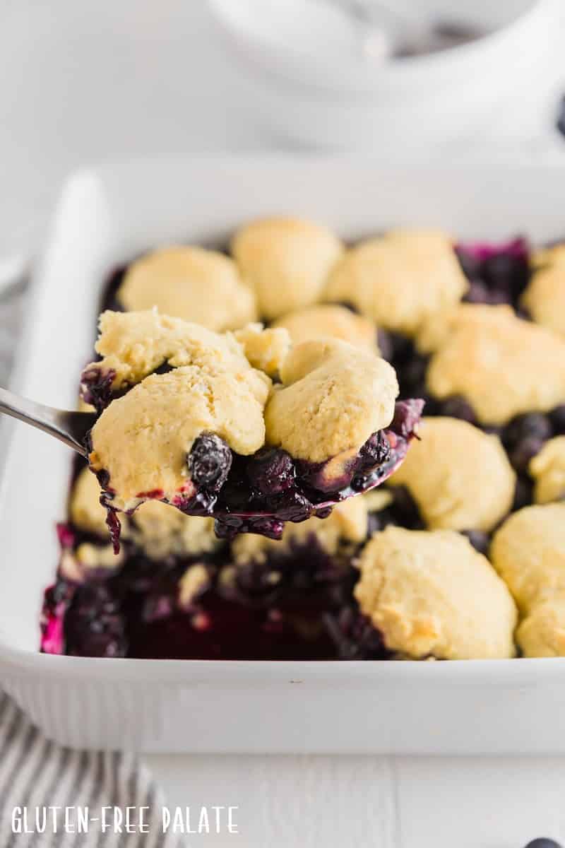 a close up of a spoon full of gluten-free blueberry cobbler