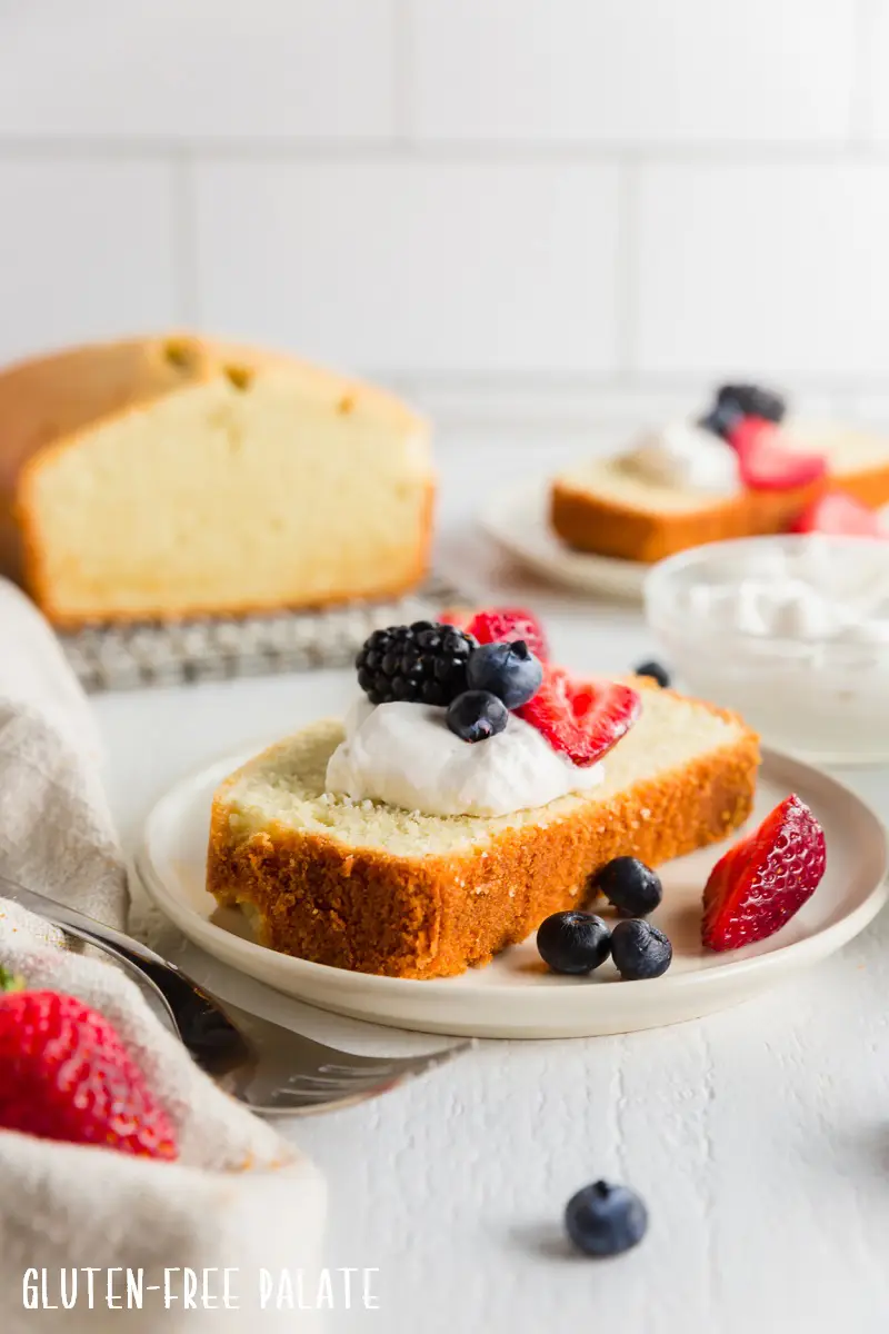 a slice of gluten free pound cake topped with whipped cream and berries