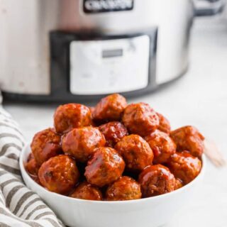 crockpot bbq meatballs in a white bowl in front of a crockpot