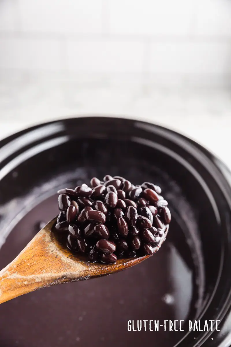 a wooden spoon full of crockpot black beans