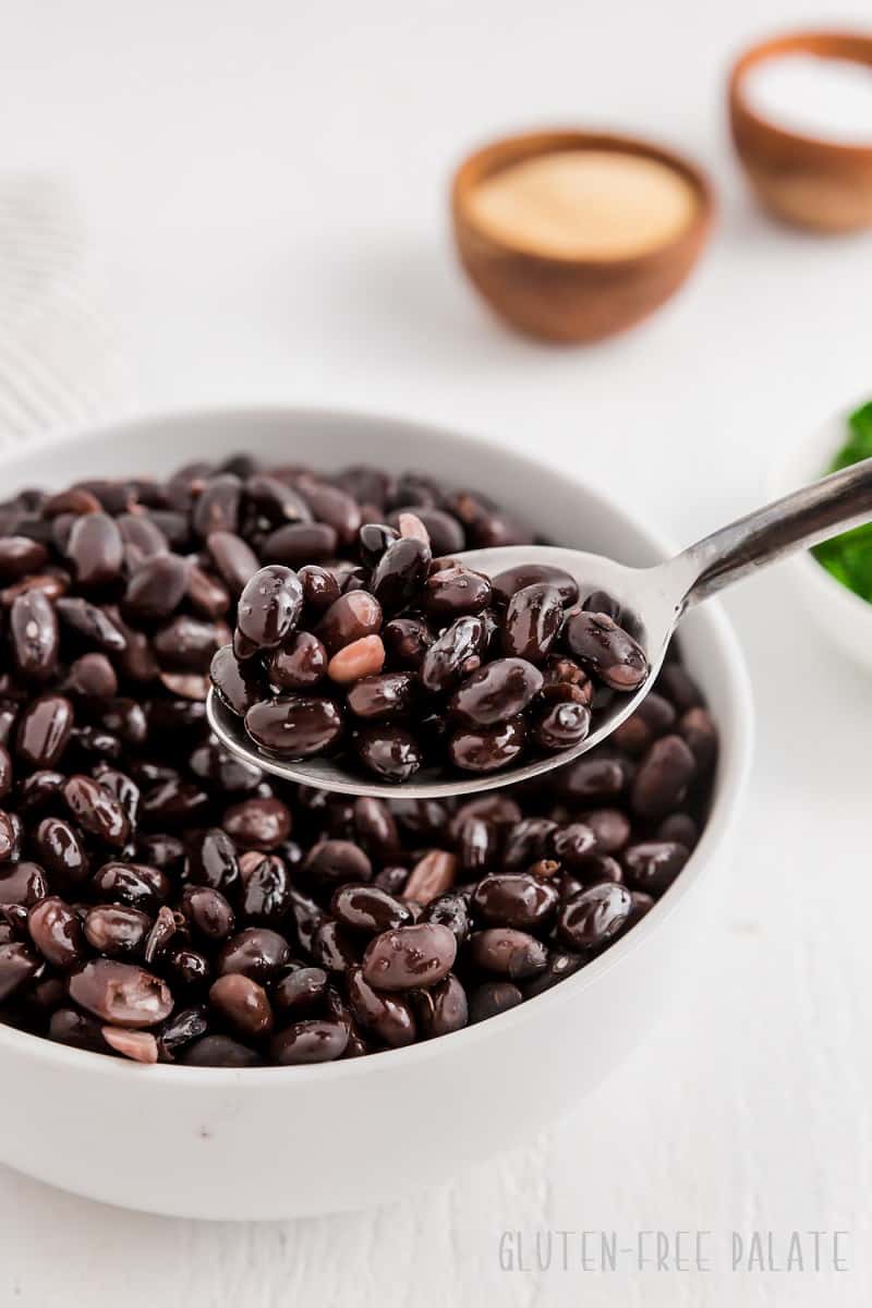 a spoonful of crockpot black beans over a bowl of beans