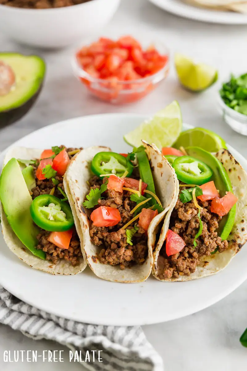 three gluten-free tacos on a white plate.