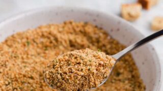 a spoonful of gluten free breadcrumbs over a bowl of bread crumbs