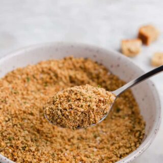 a spoonful of gluten free breadcrumbs over a bowl of bread crumbs