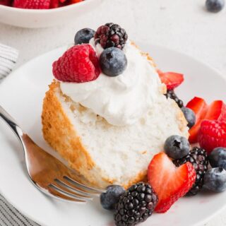a slice of gluten free angel food cake with whipped cream and berries