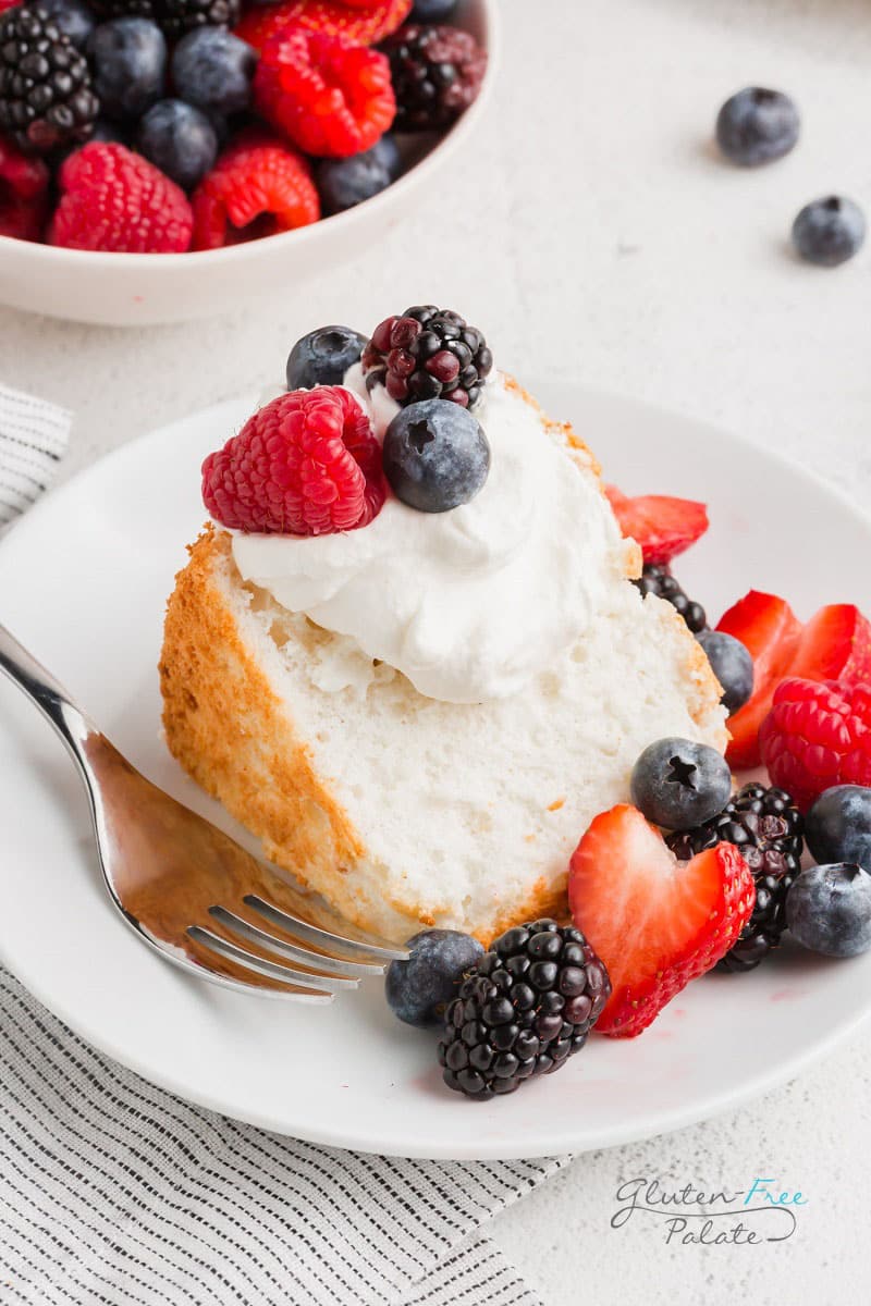a slice of gluten free angel food cake with whipped cream and berries