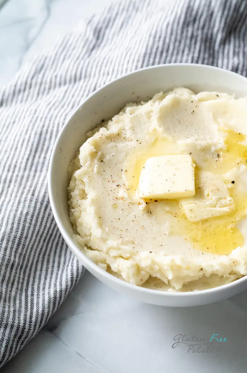 a side view of a bowl of gluten free mashed potatoes with butter on top