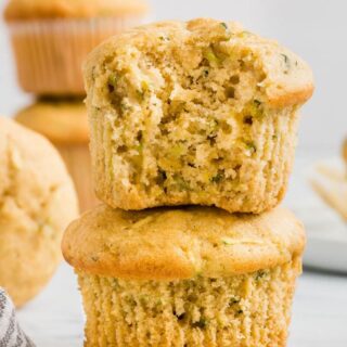 a gluten-free zucchini muffin with a bite out on top of another muffin