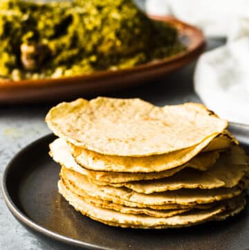 a stack of gluten-free corn tortillas on a black plate