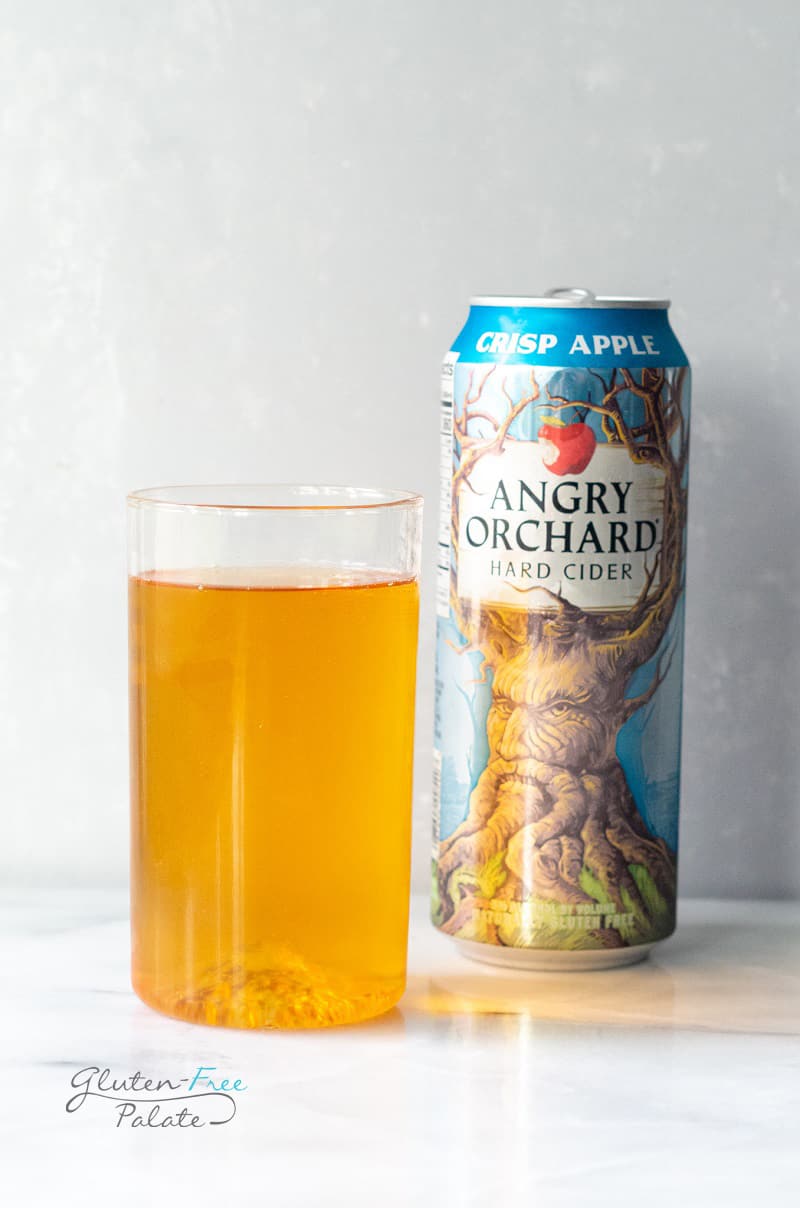 A glass of gluten free hard cider next to a can