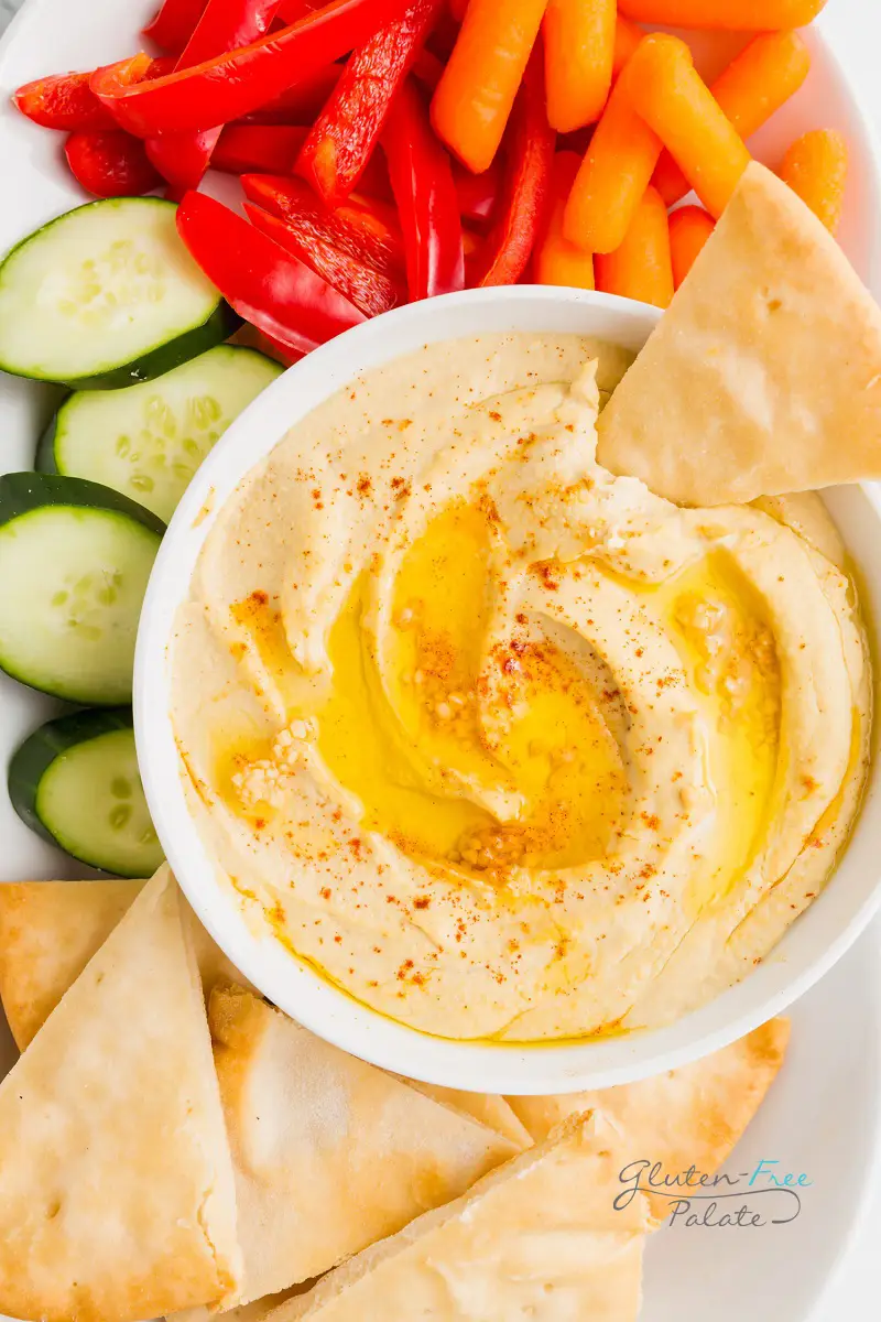 bowl of gluten free hummus with a slice of pita bread dipped in