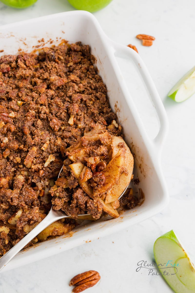 a spoon taking a serving of paleo apple crisp from the pan