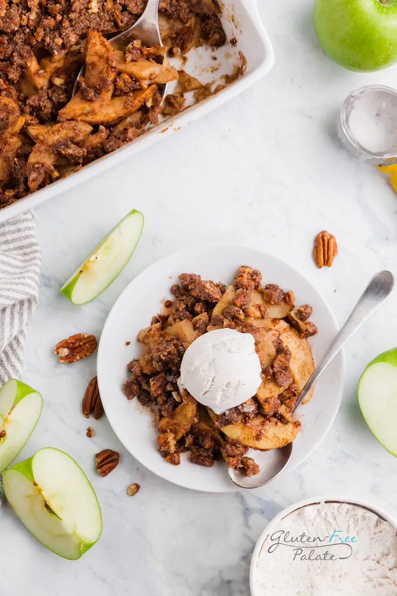 top down view of paleo apple crisp in a white bowl topped with vanilla ice cream