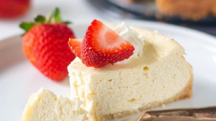 a slice of gluten free cheesecake on a white plate with a bite out and a fork