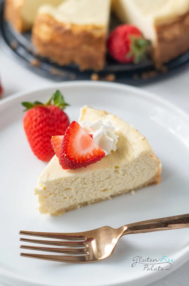 a slice of gluten-free cheesecake on a white plate with strawberries on top