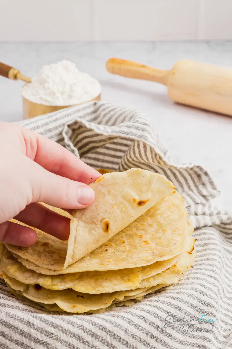 a hand folding up a gluten free tortilla