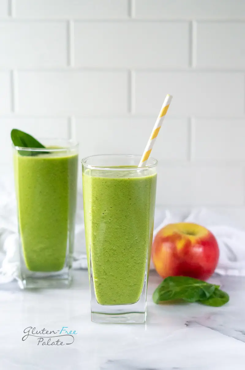 apple spinach smoothie in a glass with a straw