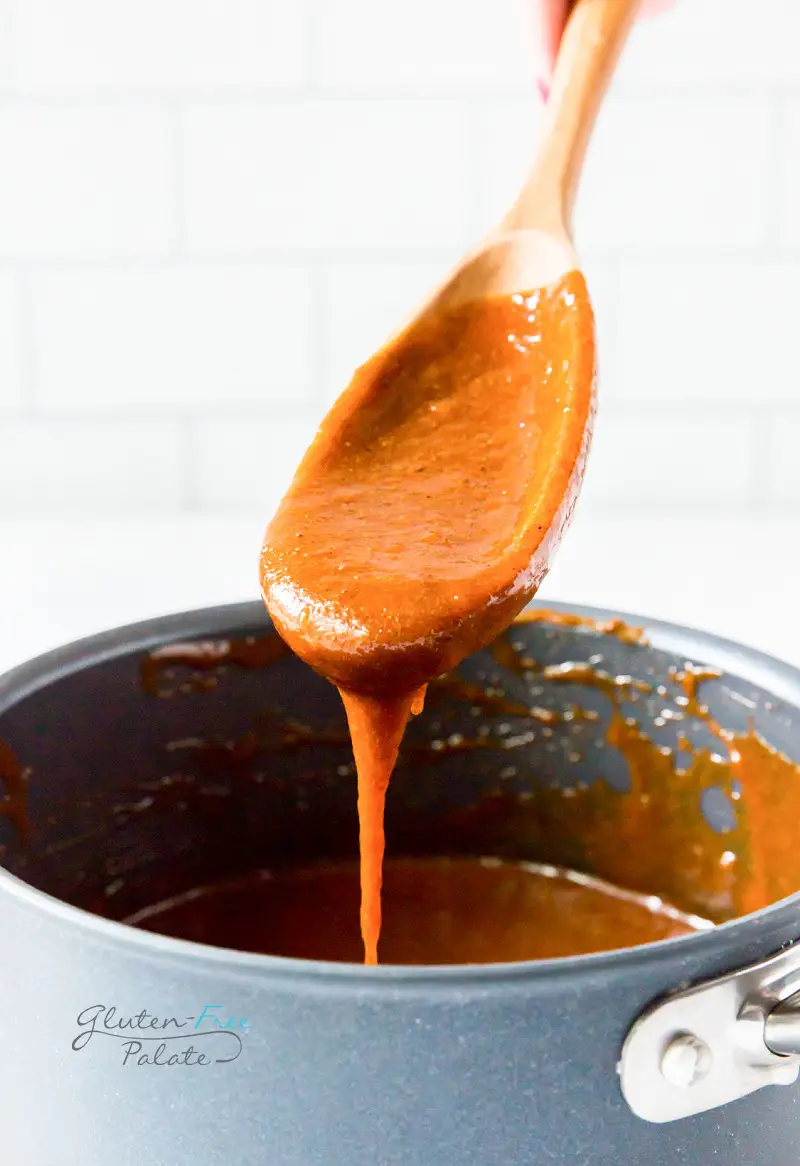 a wooden spoon with gluten-free enchilada sauce