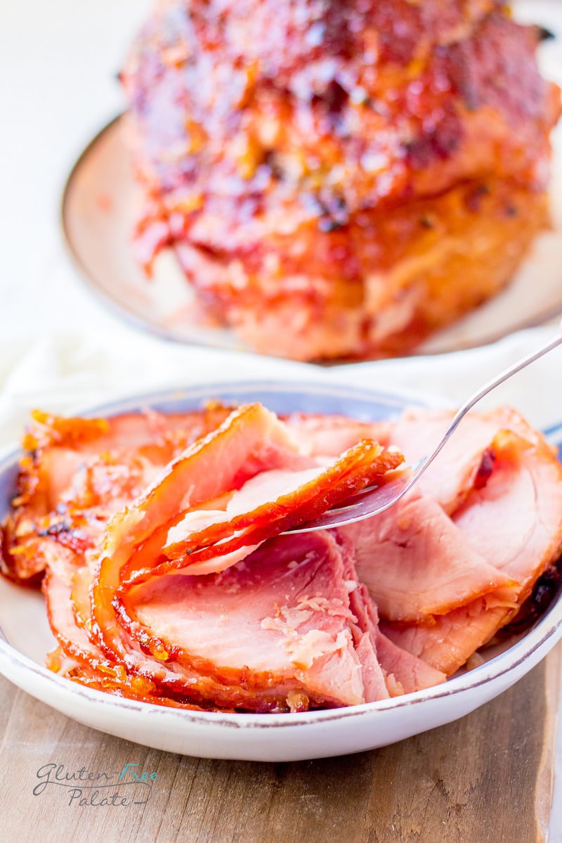 sliced spiral gluten free ham on a white plate with a fork