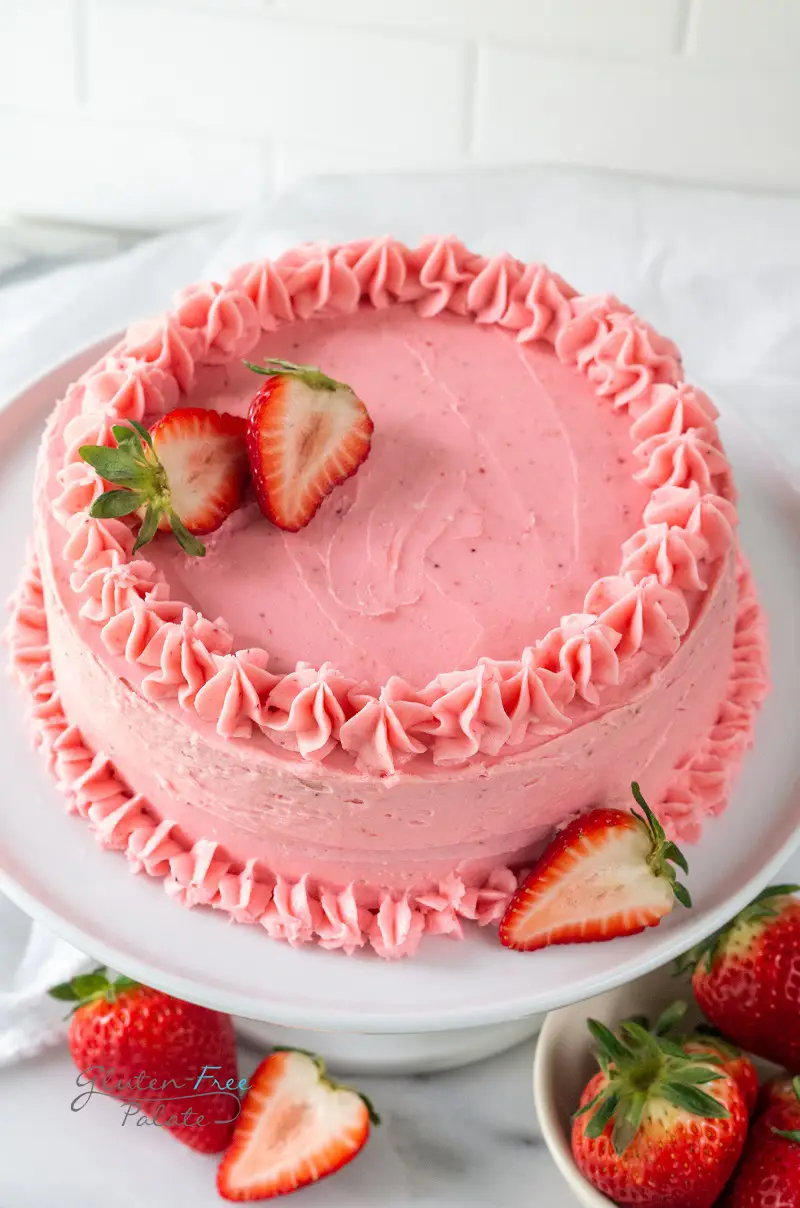 angled view of a gluten-free strawberry cake on a white cake platter
