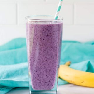 chia seed smoothie in a glass with a blue striped straw