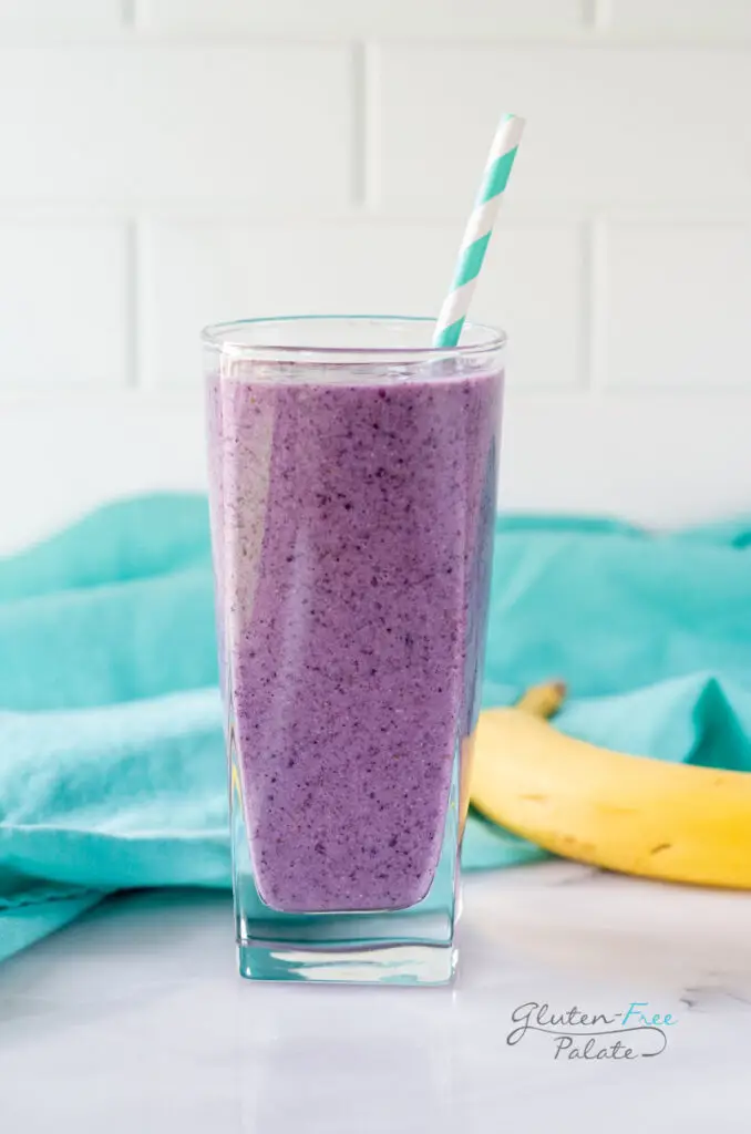 chia seed smoothie in a glass with a blue striped straw