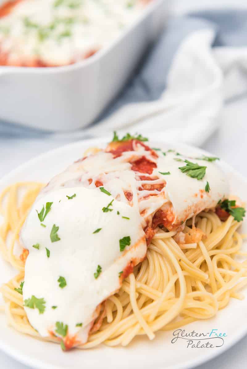 a plate of spaghetti topped with cheesy chicken parmesan.