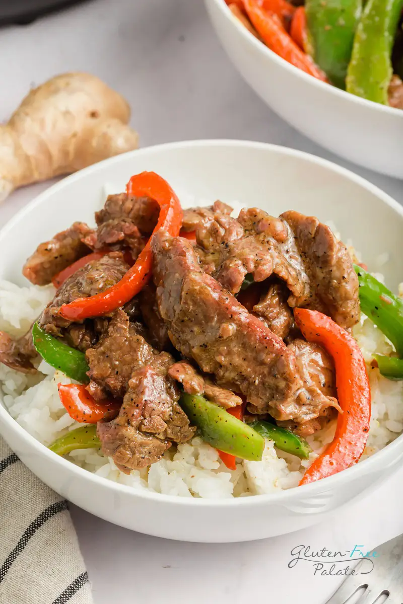 closeup view of pepper steak and rice in a white bowl on a counter
