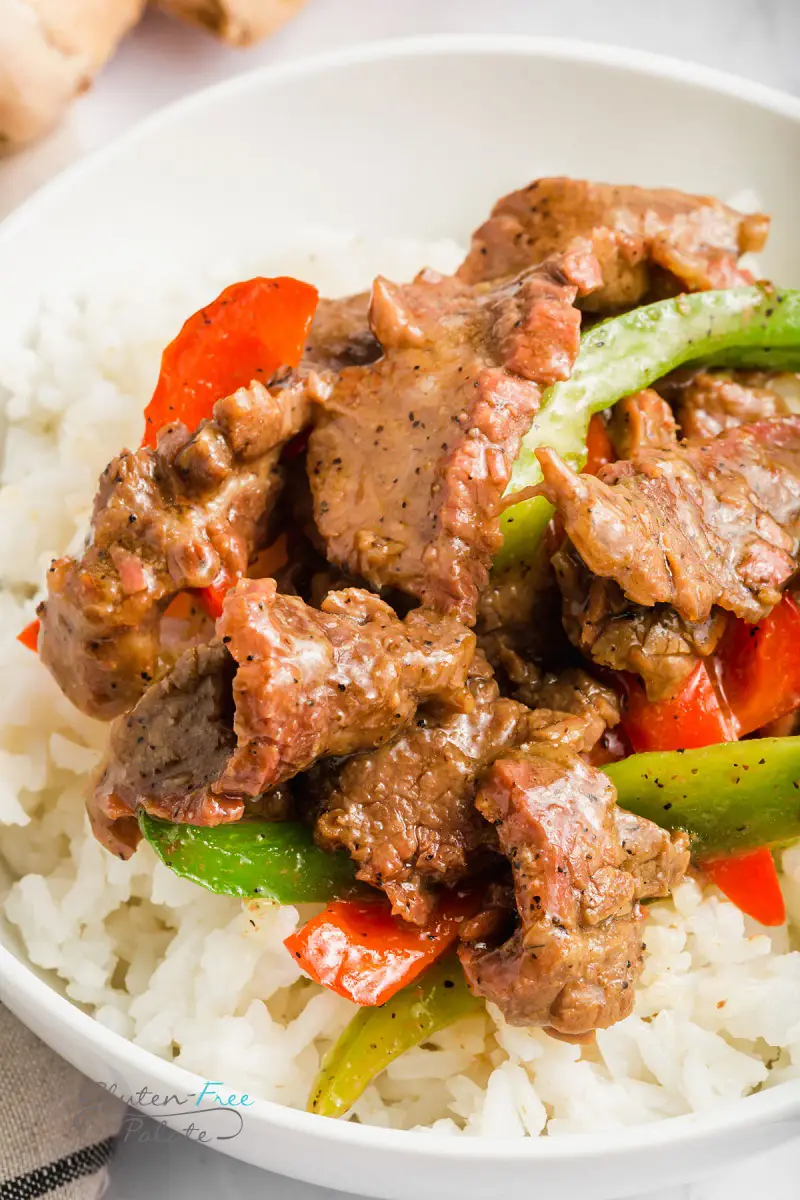 closeup view of sliced steak and peppers with rice.