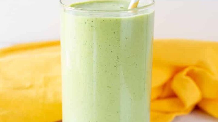 pineapple spinach smoothie in a glass with a straw