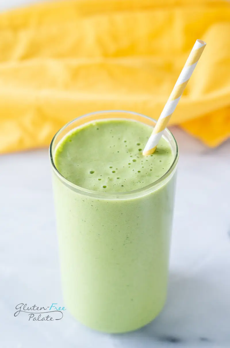 side view of a pineapple spinach smoothie in a glass with a straw