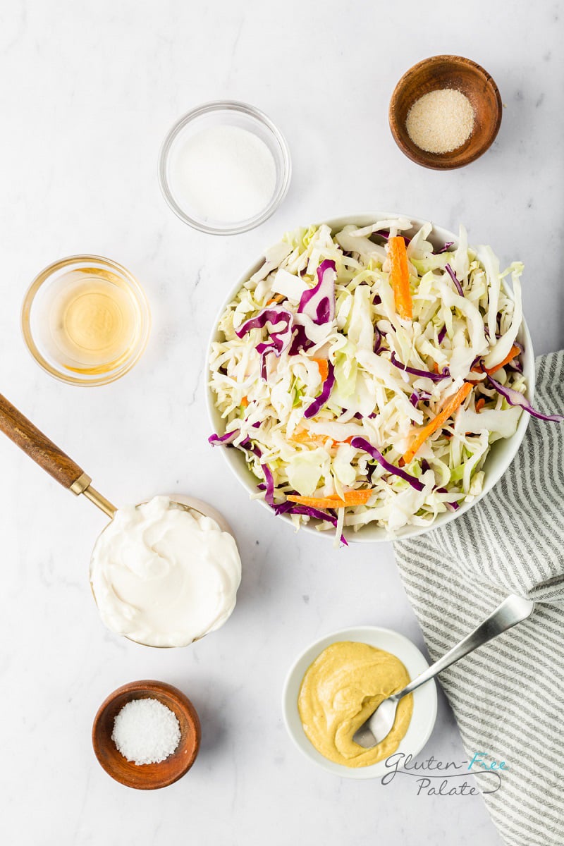 top down shot of the ingredients needed to make gluten free coleslaw, all in separate bowls.