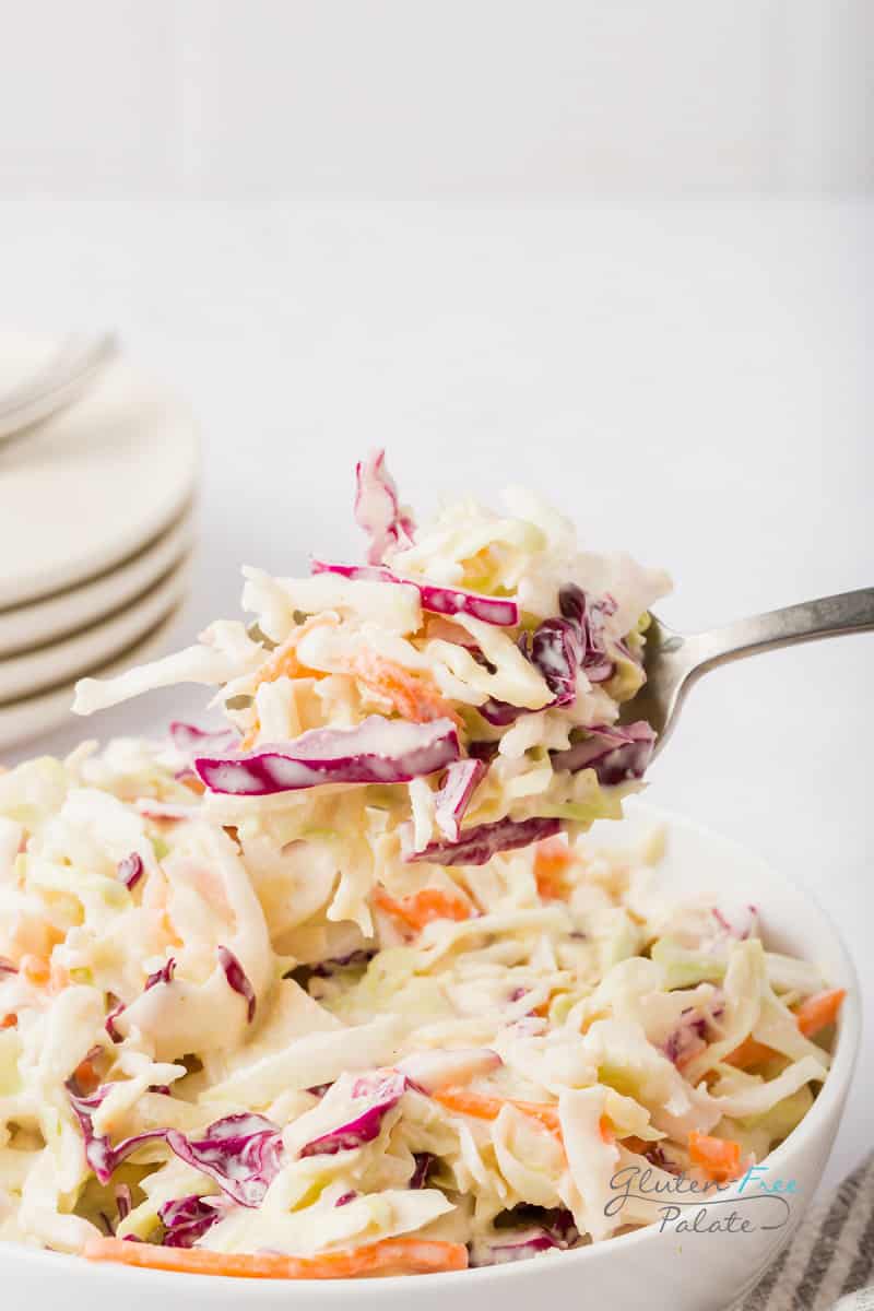 a bowl of cole slaw being eaten with a fork.