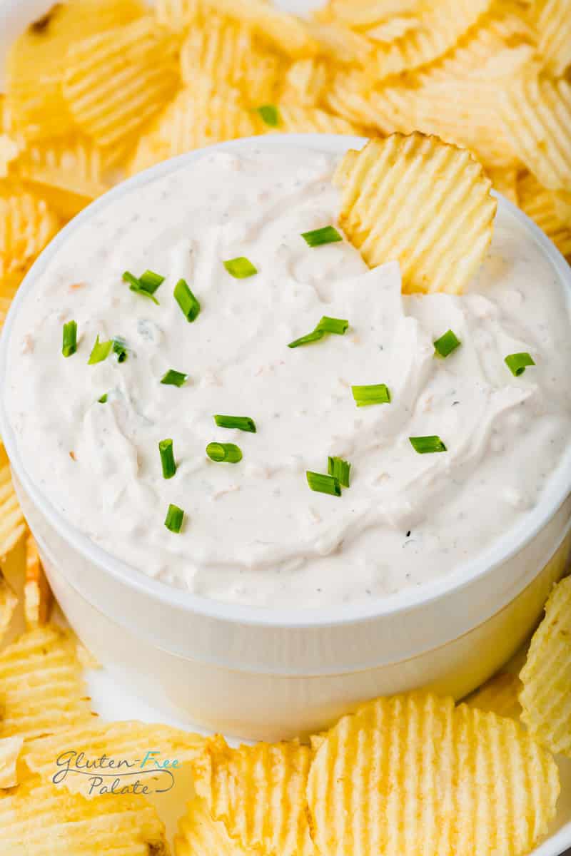 a dish of creamy onion dip surrounded by potato chips.