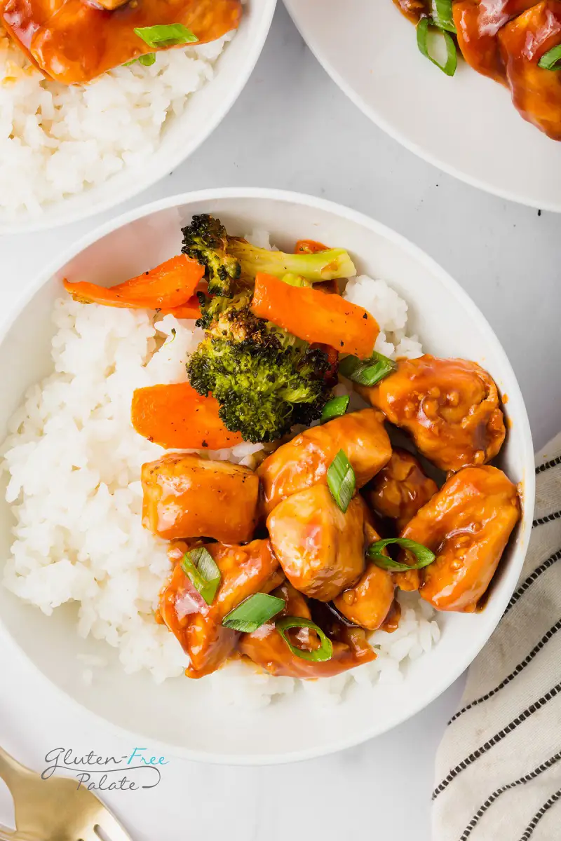 a bowl of white rice topped with gluten-free teriyaki chicken, carrots, and broccoli