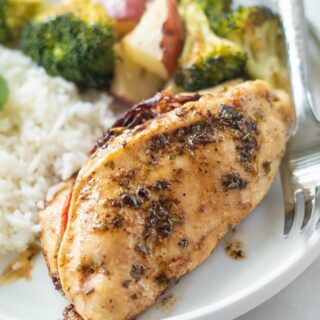 Stuffed chicken breast on a dinner plate with rice and roasted vegetables.