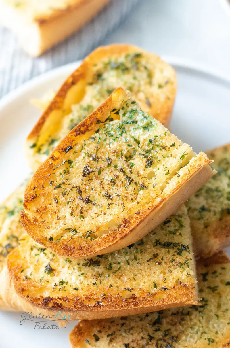 a closeup view of a plate of gluten-free garlic bread slices cut in half and stacked on top of each other.