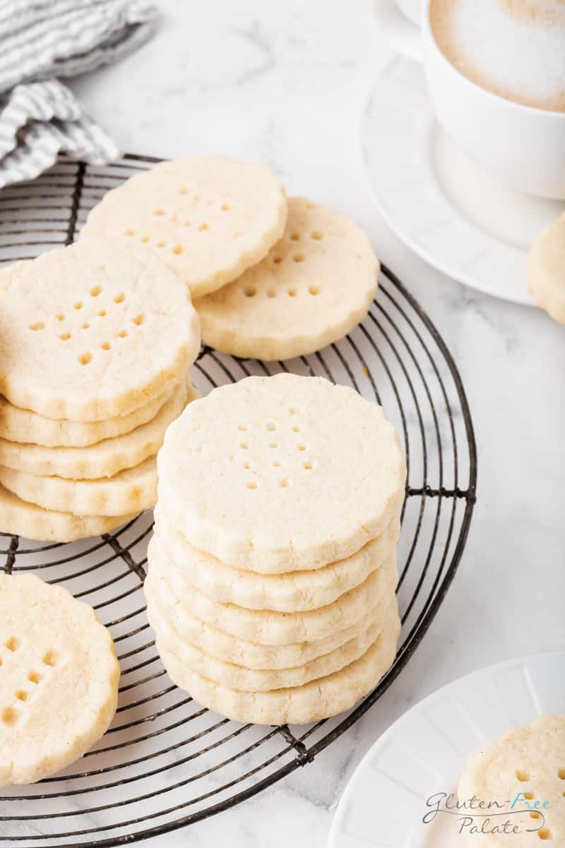 stacks of scalloped round shortbread cookies on a round, black cooling rack.