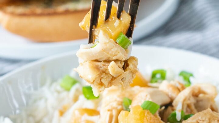 Shredded Hawaiian chicken with pineapple and green onions mixed with rice, being eaten with a fork.