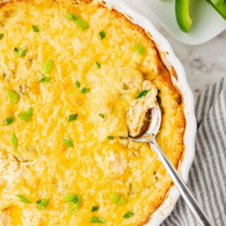a large round dish filled with baked cheese dip and topped with green onions. Served next to a plate of cheese crisps and sliced green peppers