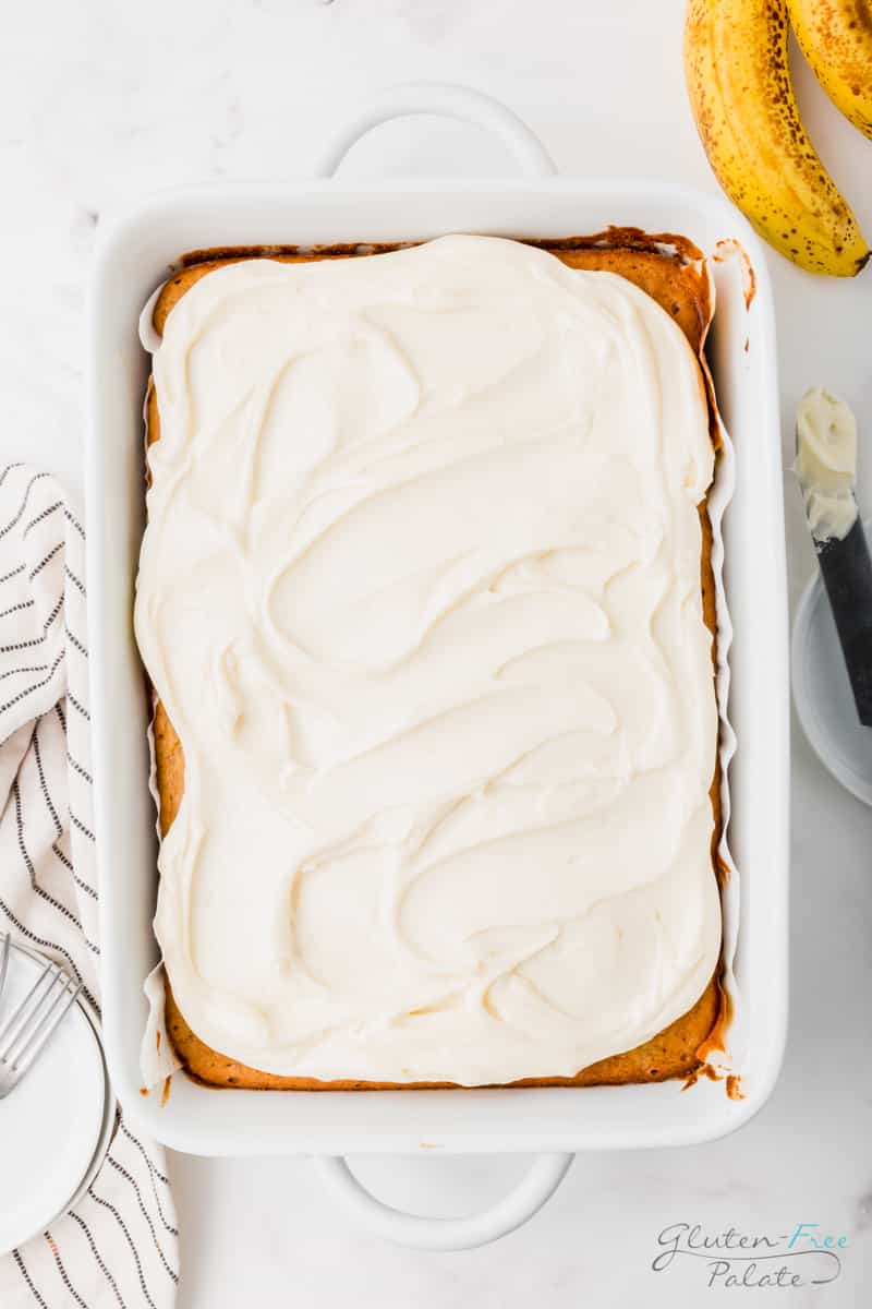 a rectangular baking dish of gluten-free banana cake topped with white frosting